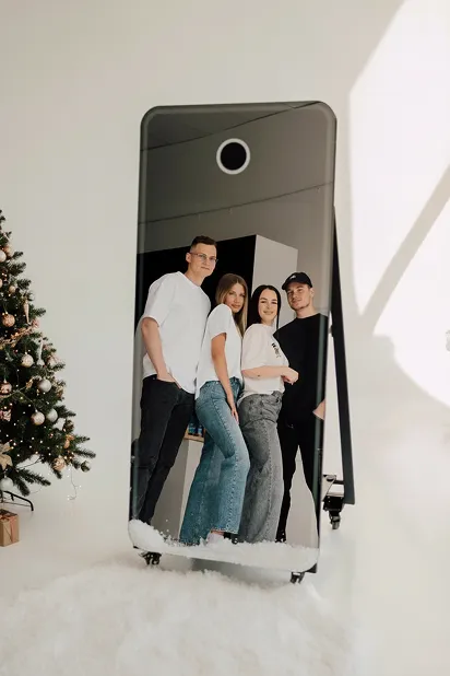 Photo booth set up beside a Christmas tree with guests posing at a company party