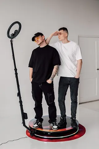 Two guests standing on the PicMe 360 video booth platform with the camera arm around them