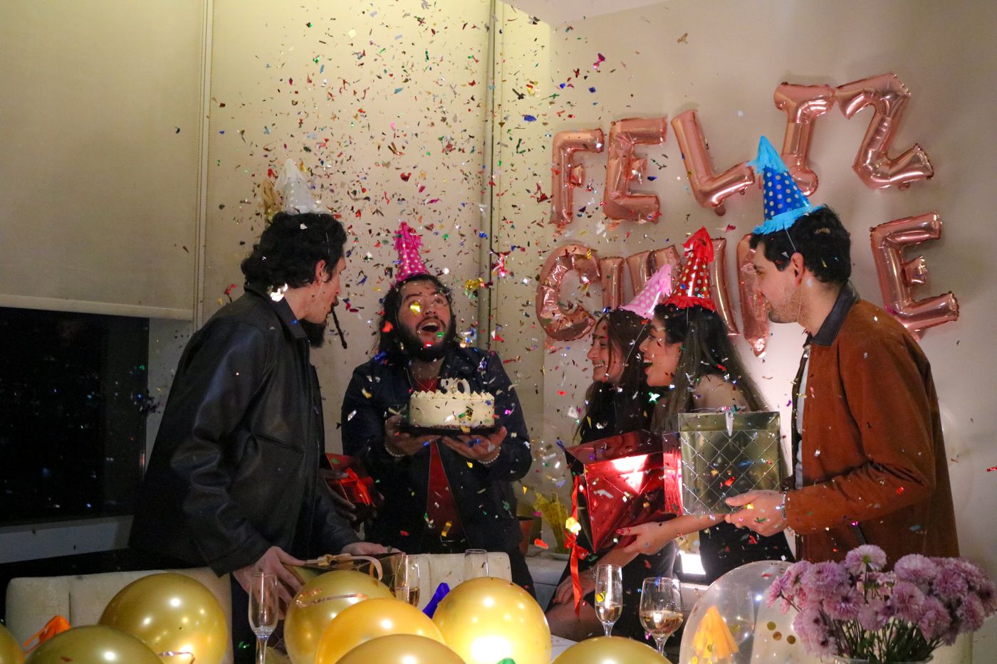 Invitados celebrando un cumpleaños con tarta y regalos